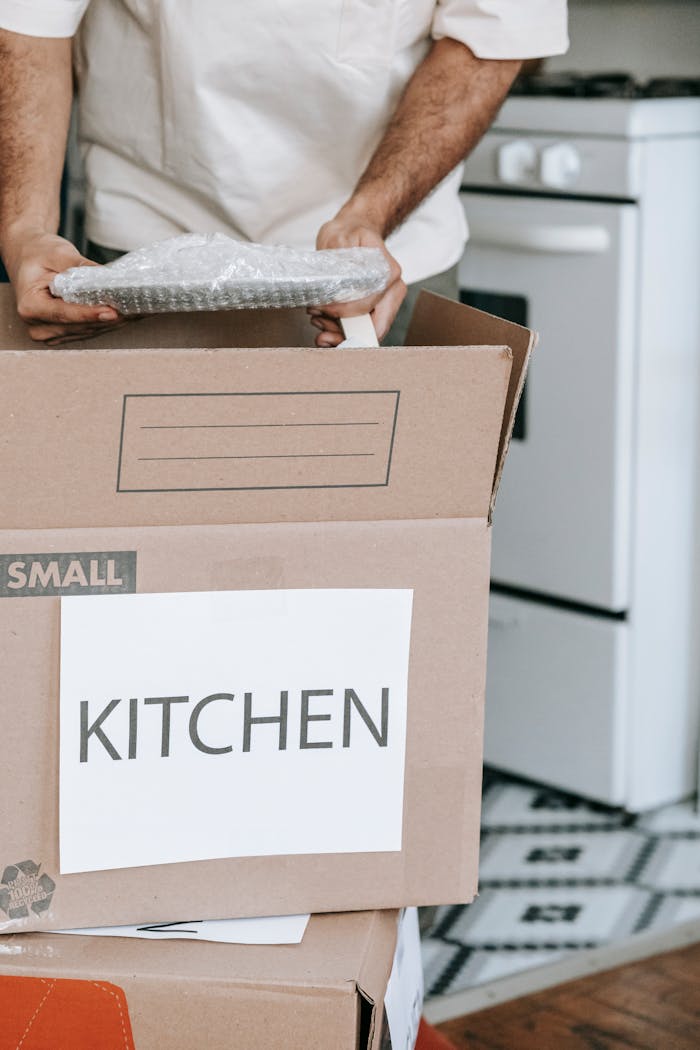 hero-about Man packing kitchenware into labeled boxes for a home relocation.